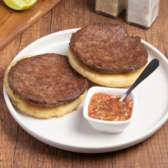 Arepas con carne acompañas de ají servidas sobre un plato