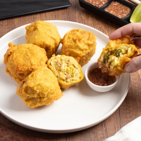 Papas rellenas acompañadas de ají servidas sobre un plato